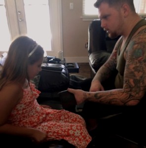 Sgt. Tovet shows Eric’s daughter, 8, how he works on his fine motor skills by making wallets. 